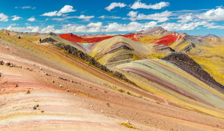 montagne arc-en-ciel de Palcoyo aux teintes rouges, jaunes et roses sous un ciel bleu