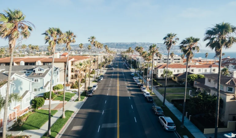 rue californienne avec palmiers, maisons et vue sur l'océan en arrière-plan