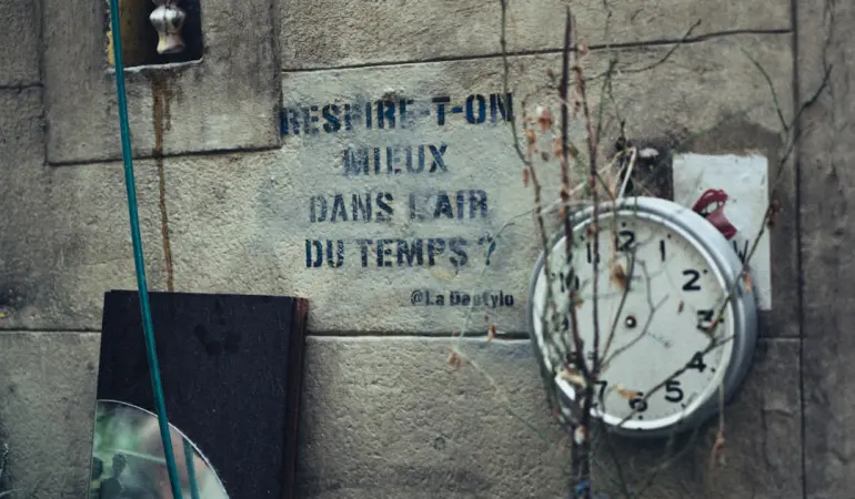 Old clock and graffiti on a weathered wall.