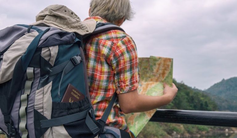 A backpacker examining a map against a scenic outdoor landscape. Adventure awaits.