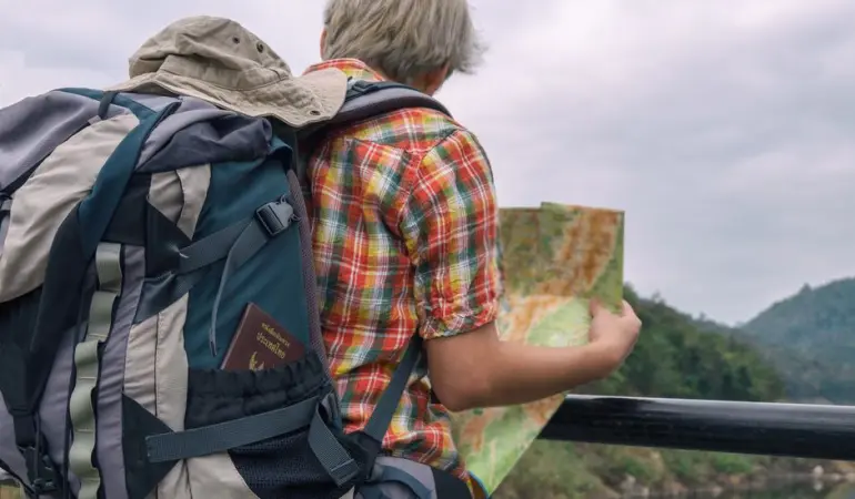 A backpacker examining a map against a scenic outdoor landscape. Adventure awaits.