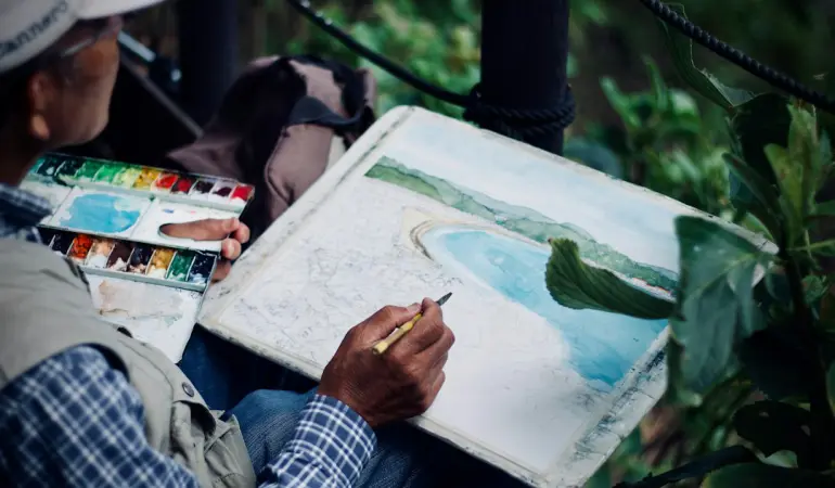 man holding brown and black pen painting seashore
