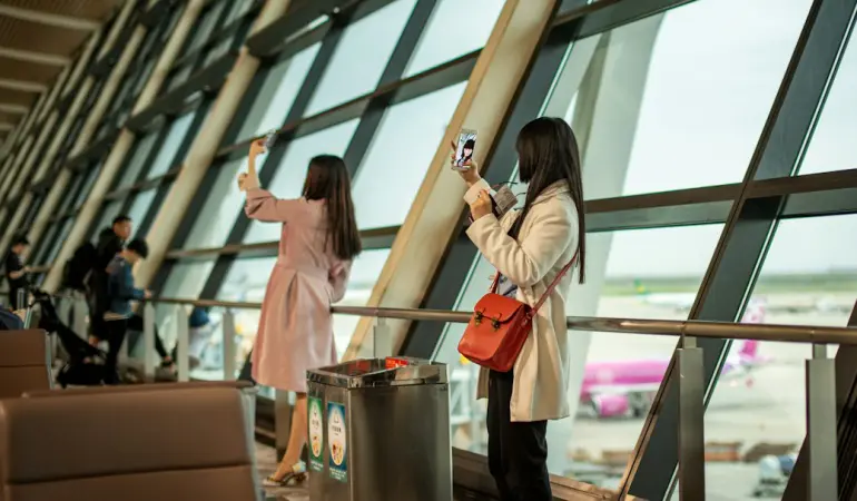 Two women taking selfies by airport window